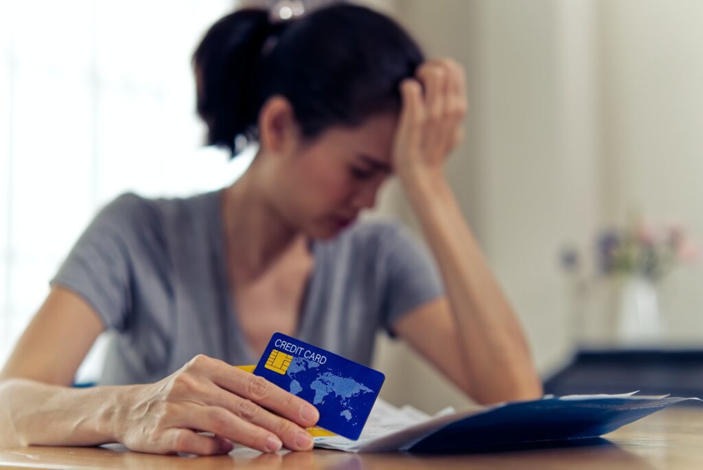 Asian woman holding credit card worry about find money to pay credit card debt and all loan bills.